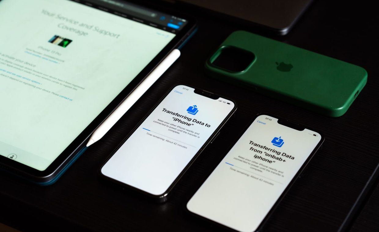 High-angle view of digital devices including iPhones and an iPad on a desk, showcasing data transfer.