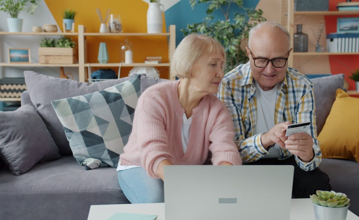 Elderly couple shopping online with credit card and laptop.
