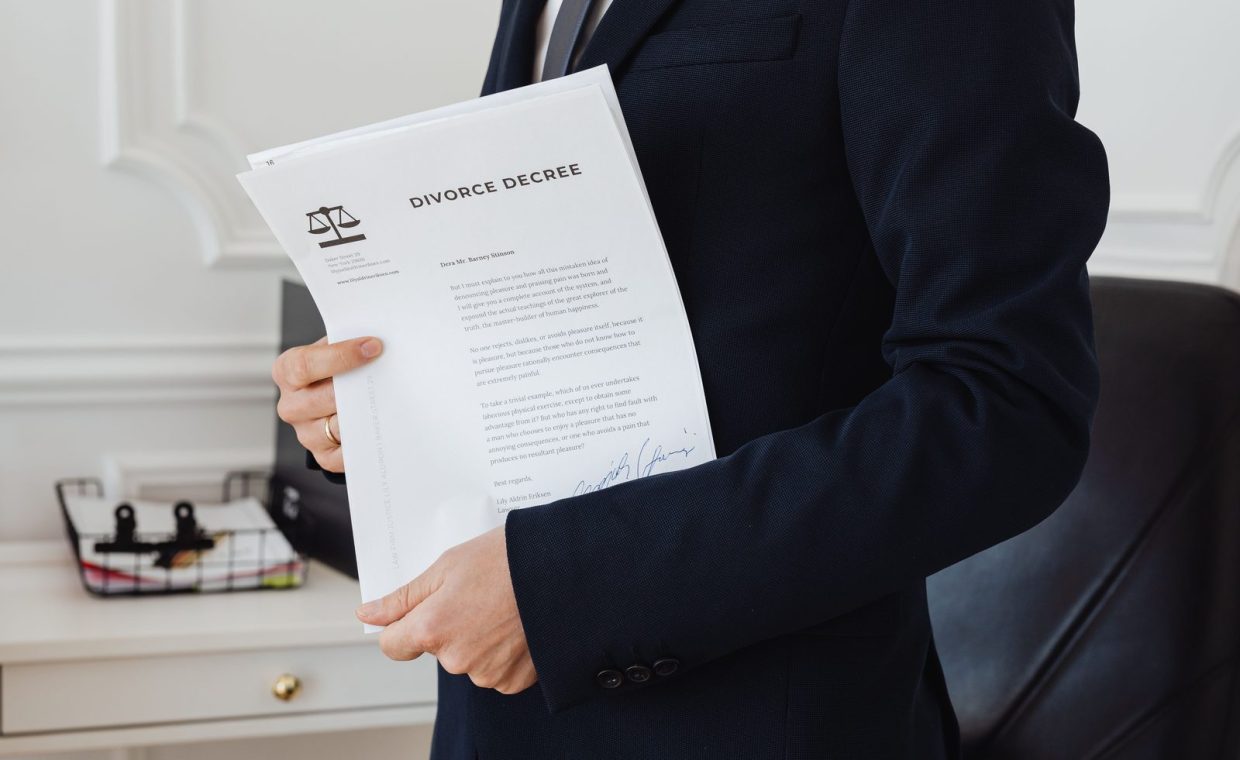 A person holding a divorce decree in an office setting, symbolizing legal proceedings.