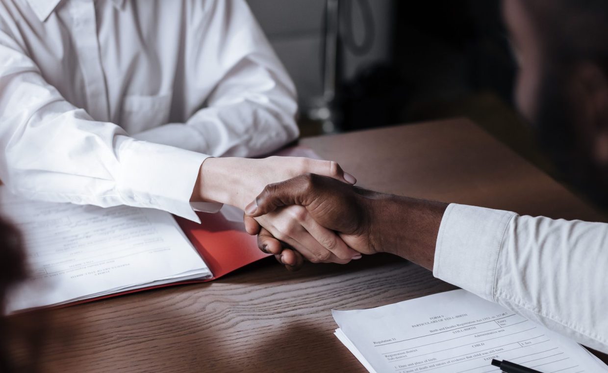 Close-up of a diverse business handshake over documents, symbolizing agreement and collaboration.