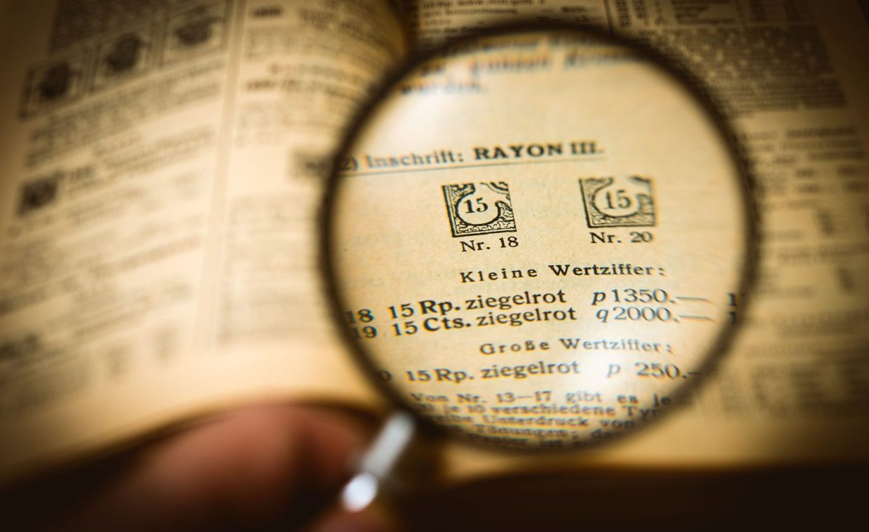 Detailed view of a book page magnified by a glass, enhancing text clarity.