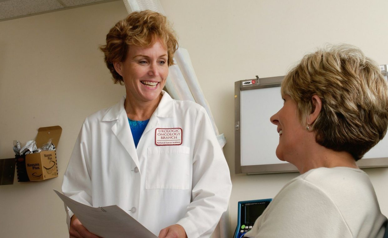 woman in white scrub suit holding gray laptop computer
