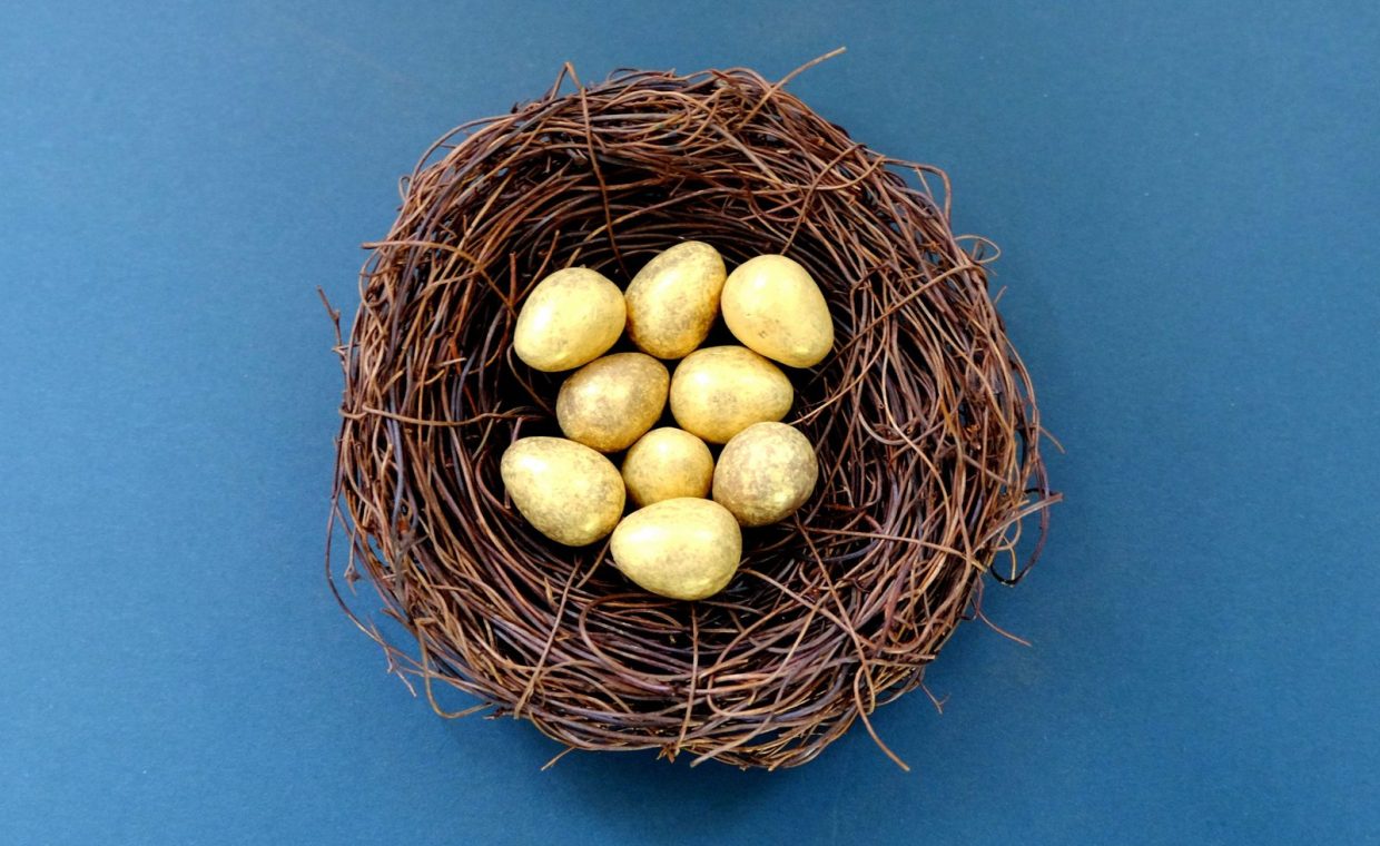 A nest filled with golden eggs placed on a solid blue surface, perfect for Easter themes.