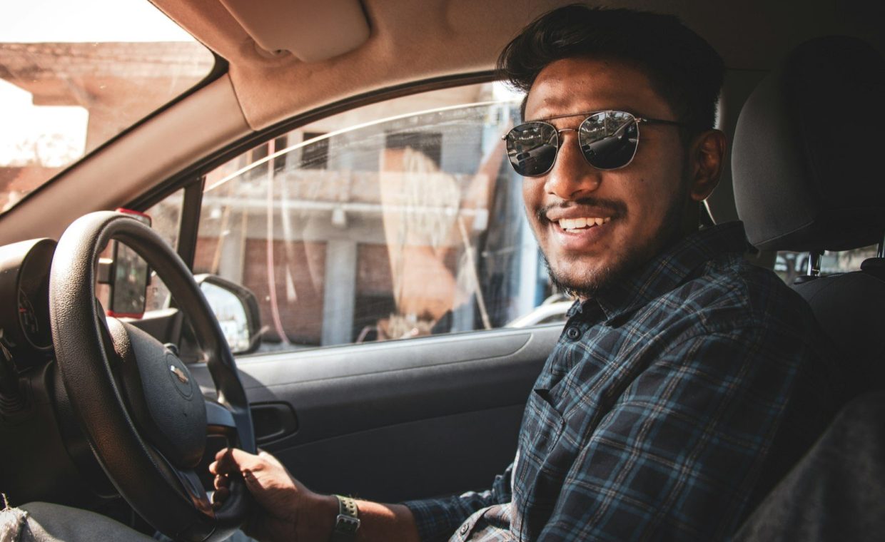 man in black and white plaid dress shirt wearing black sunglasses driving car