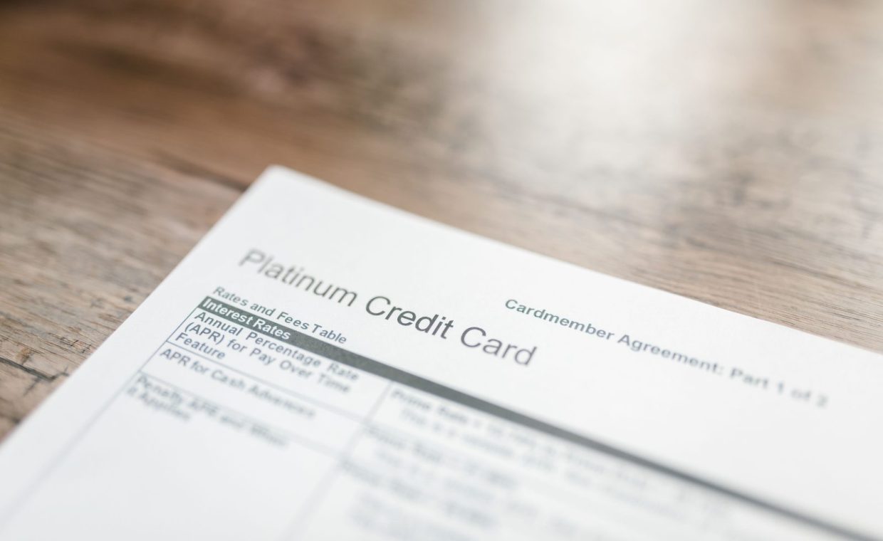 Close-up of a platinum credit card document with interest rates table on a wooden surface.