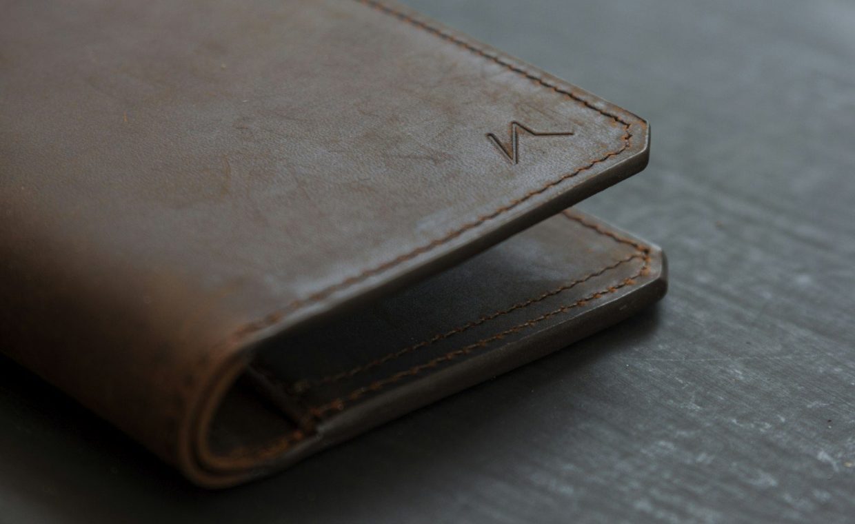 brown leather bifold wallet on gray wooden table