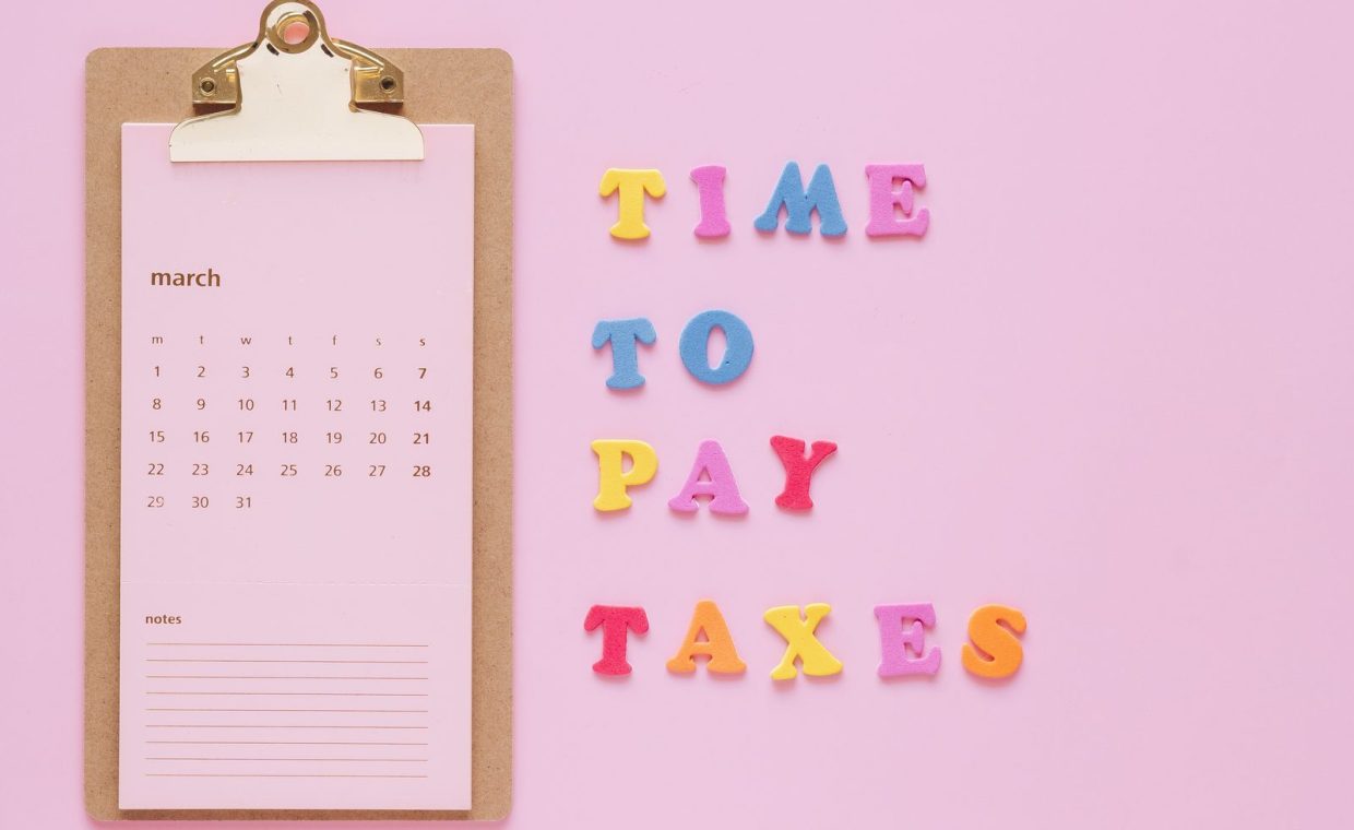 Colorful tax reminder on clipboard against a pink background for March