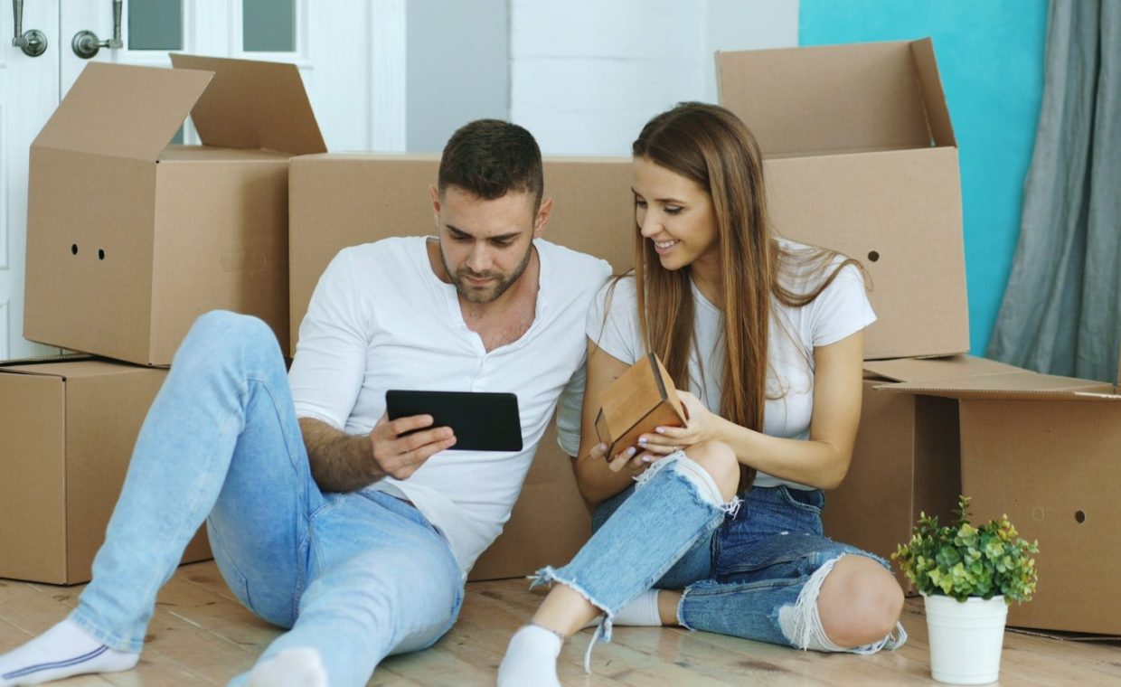 Couple looking at tablet surrounded by moving boxes