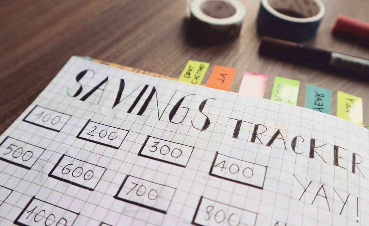 Close-up of a handmade savings tracker with colored tabs on a wooden table, ideal for financial planning visuals.