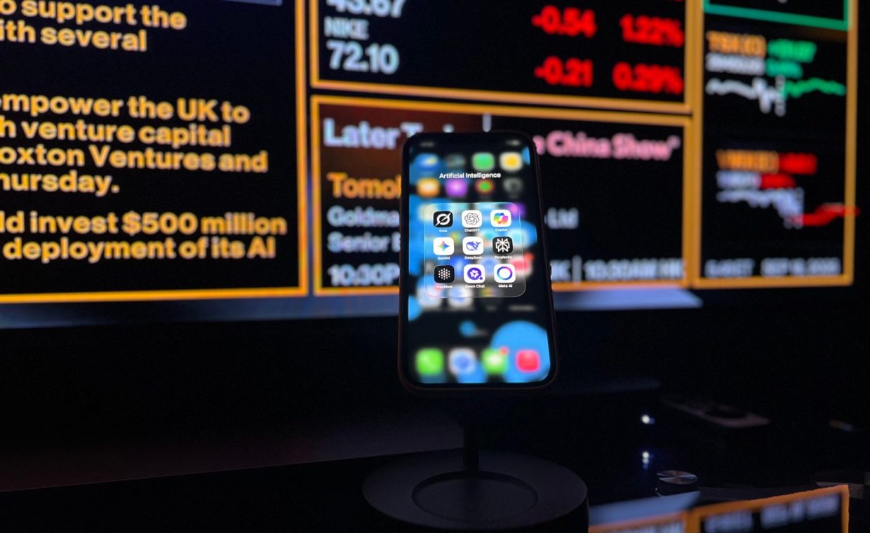 Smartphone displaying AI apps in front of a financial data screen in London.