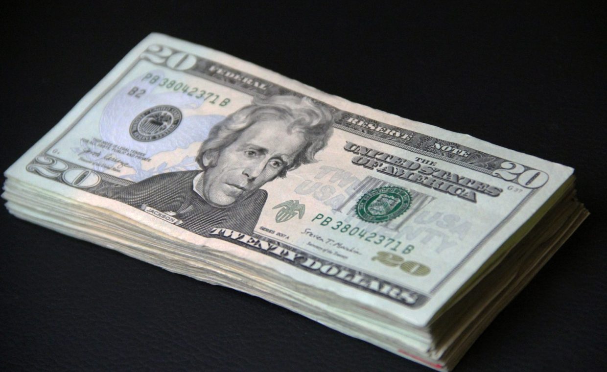 A close-up of a stack of American 20 dollar bills against a black background, symbolizing wealth.